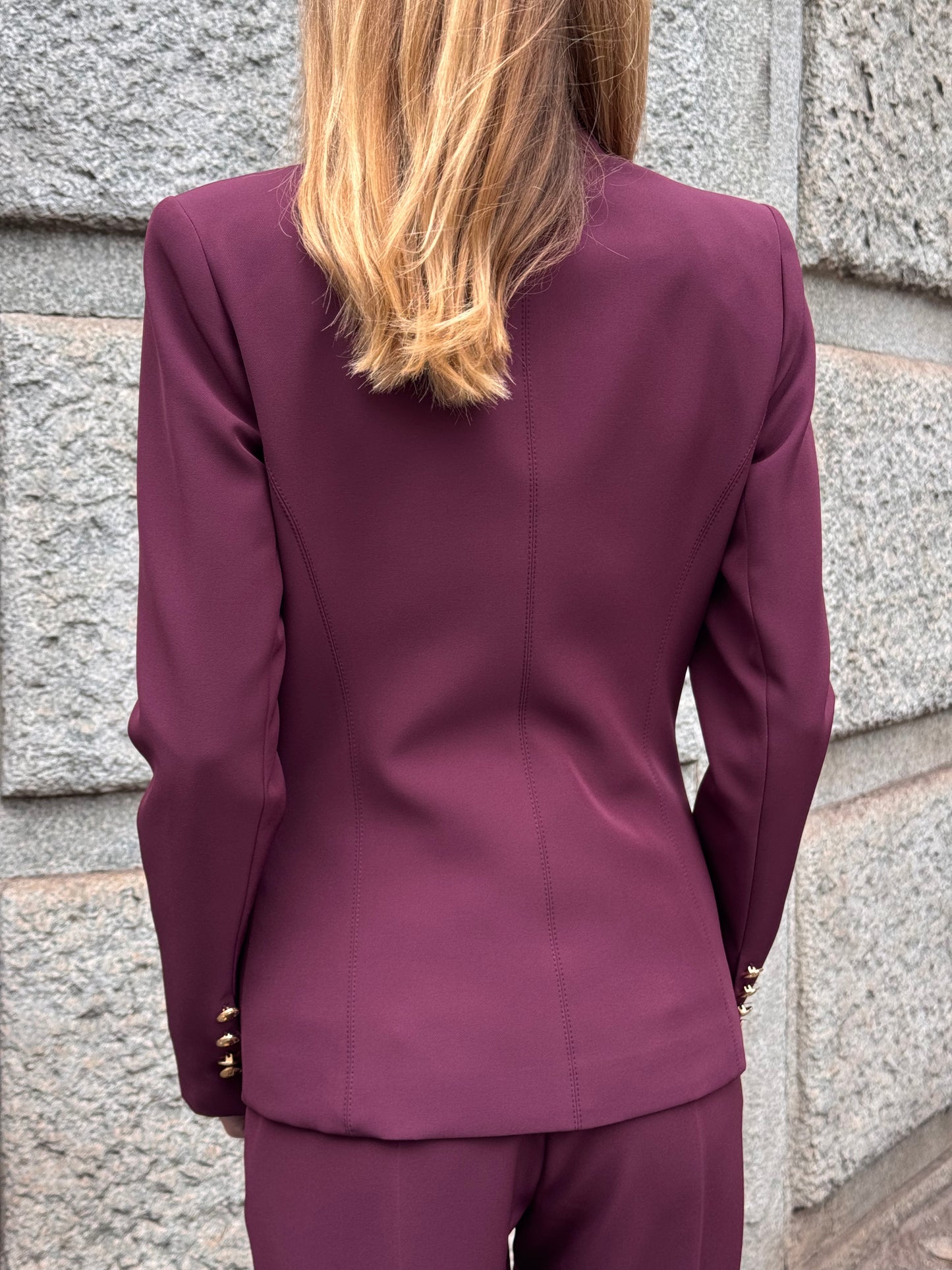 Tailleur melanzana con bottoni dorati e pantalone a zampa