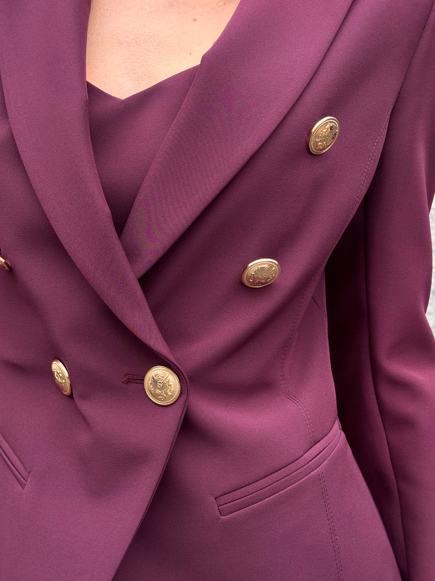 Tailleur melanzana con bottoni dorati e pantalone a zampa